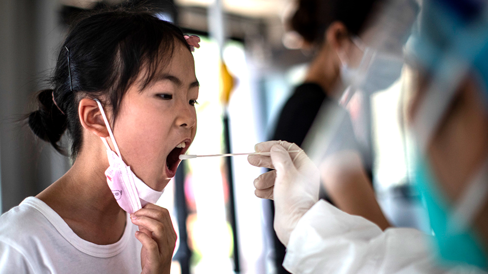 A medical worker takes samples during a mass Covid-19 test in a residential block on August 3, 2021 in Wuhan