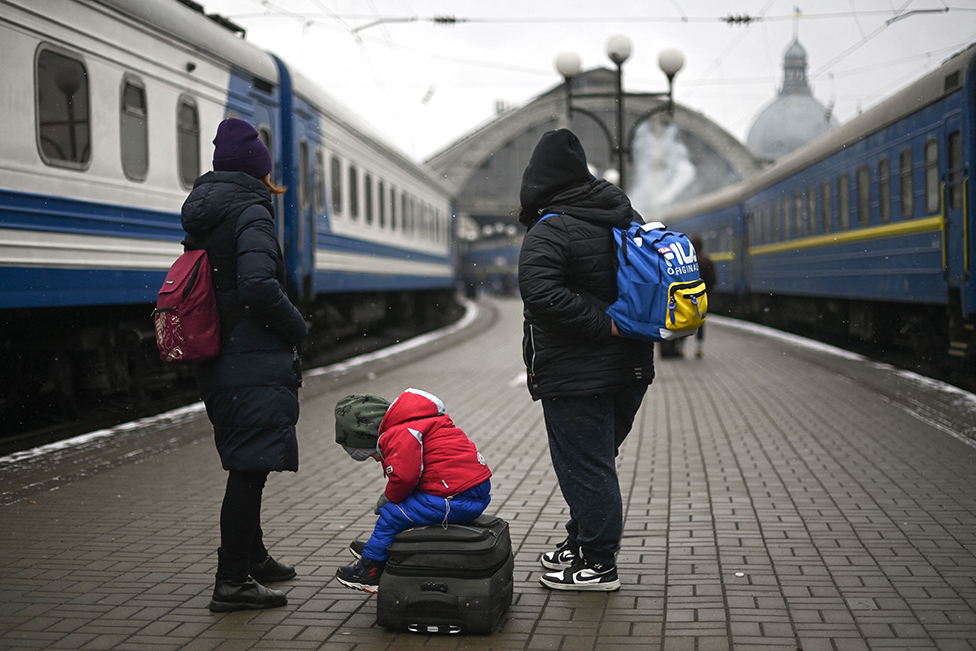 Evacuees and a child, sitting on top of a suitcase, wait for a train to Romania, at the Lviv train station, western Ukraine, on March 5, 2022.