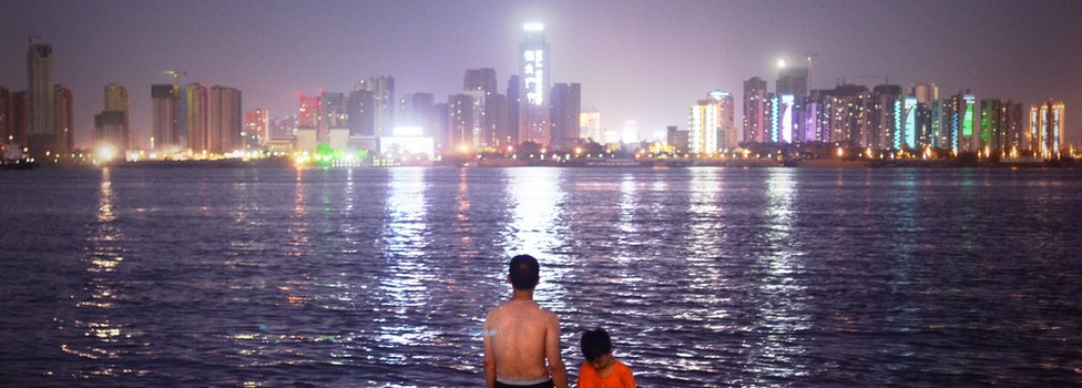 Мужчина и ребенок стоят, глядя на горизонт Уханя на реке Янцзы