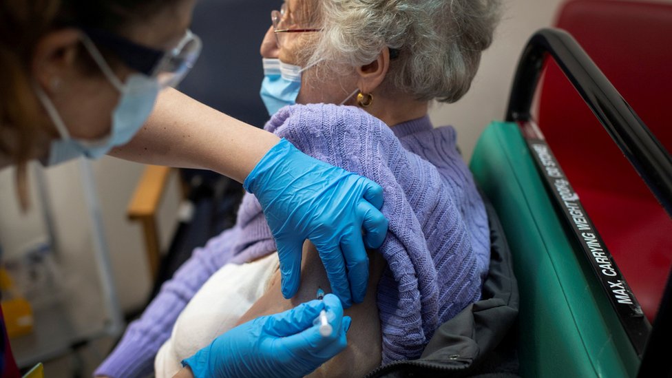 Женщина получает первую из двух прививок от Pfizer / BioNTech COVID-19 в больнице Гая