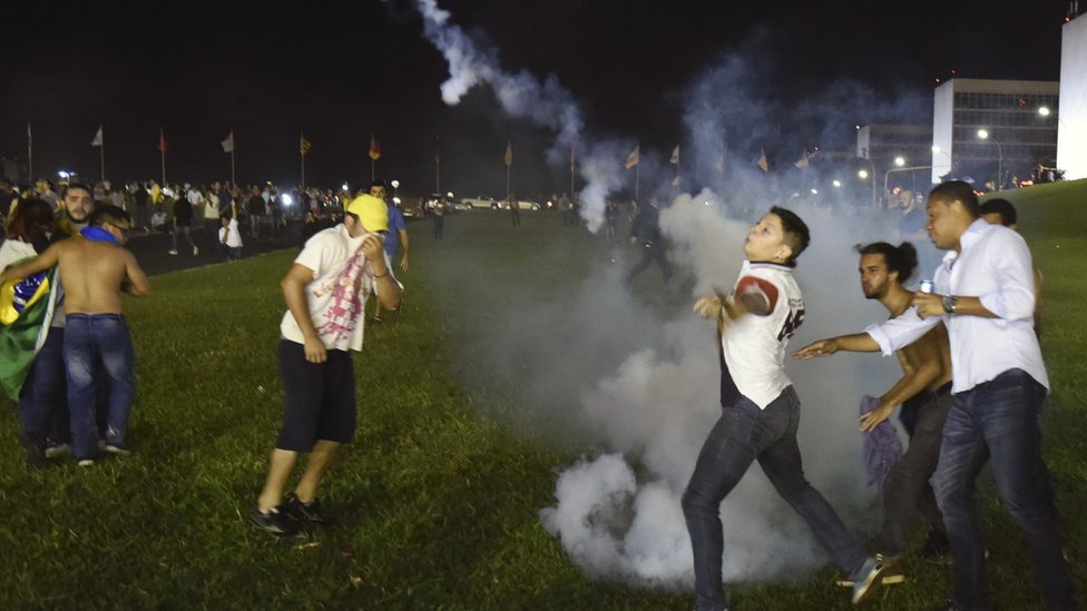 Demonstrators return tear gas to riot police during a protest against corruption in front of the Congress building in Brasilia on 16 March 2016.
