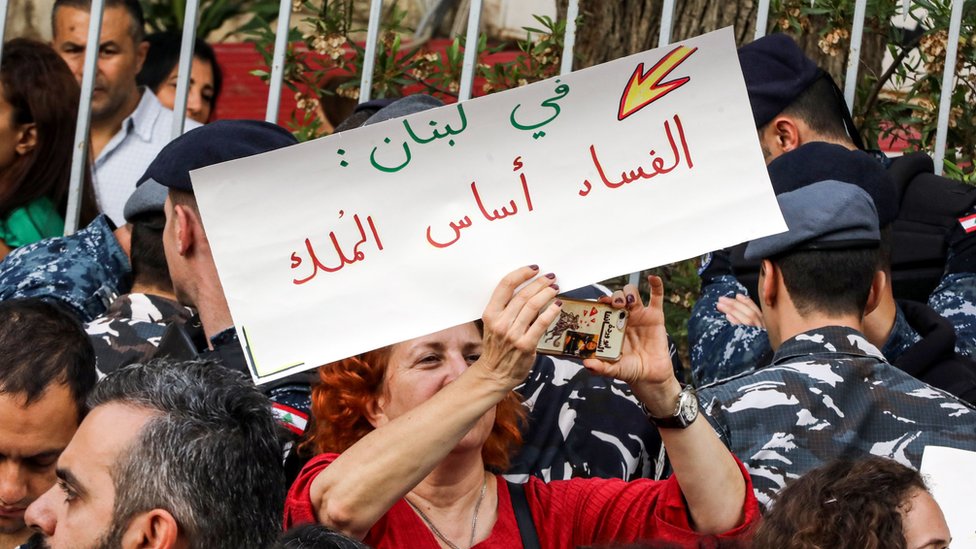 متظاهرة لبنانية ترفع لافتة منددة بالفساد