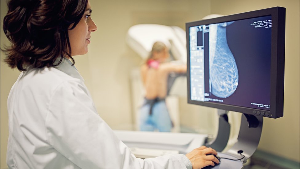 El médico está trabajando con el escáner de rayos X de mamografía en el hospital