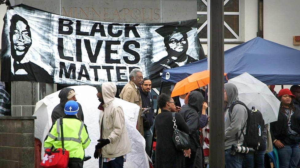 Демонстранты перед знаменем Black Lives Matter