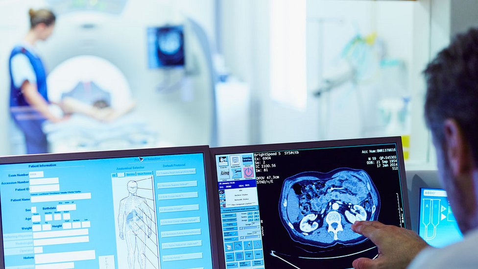 врач смотрит на компьютерную томографию на фоне человека в сканере