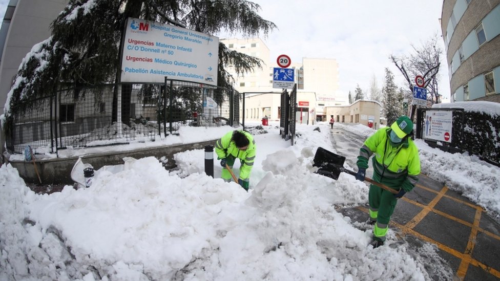 Municipal workers clear snow at entrance to Gregorio Maranon Hospital in Madrid on 10 January 2021