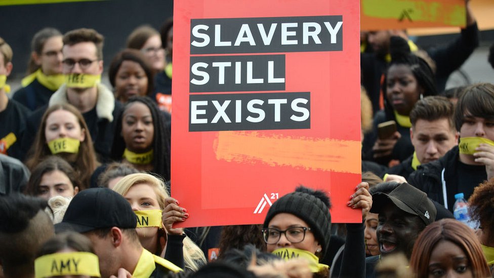 Una protesta en la que se lee un cartel que dice: "La esclavitud todavía existe".
