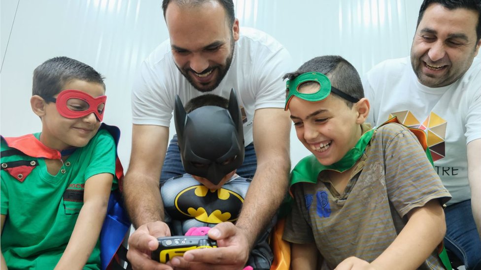 Работники благотворительности с мальчиками в костюмах супергероев