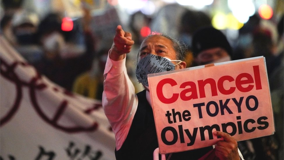Una mujer con un cartel que dice "Cancelen los olímpicos de Tokio".
