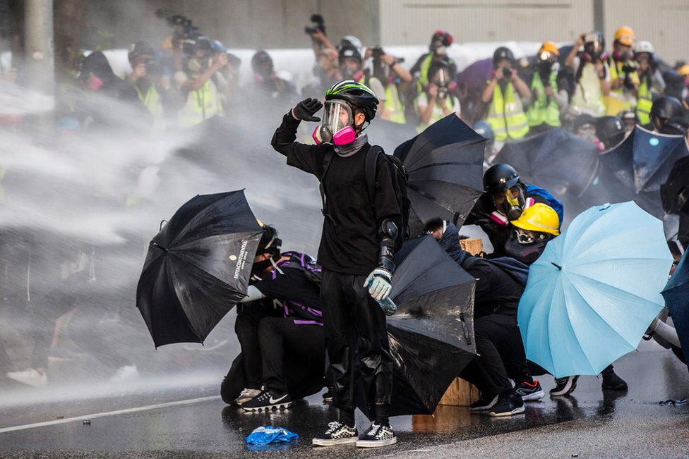 Pro-democracy protesters react as police fire water cannons outside the government headquarters in Hong Kong, 15 September 2019.