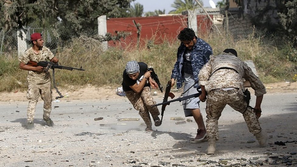 Ливийские боевики, верные Правительству национального согласия (ПНС), бегут, стреляя из своего оружия во время столкновений