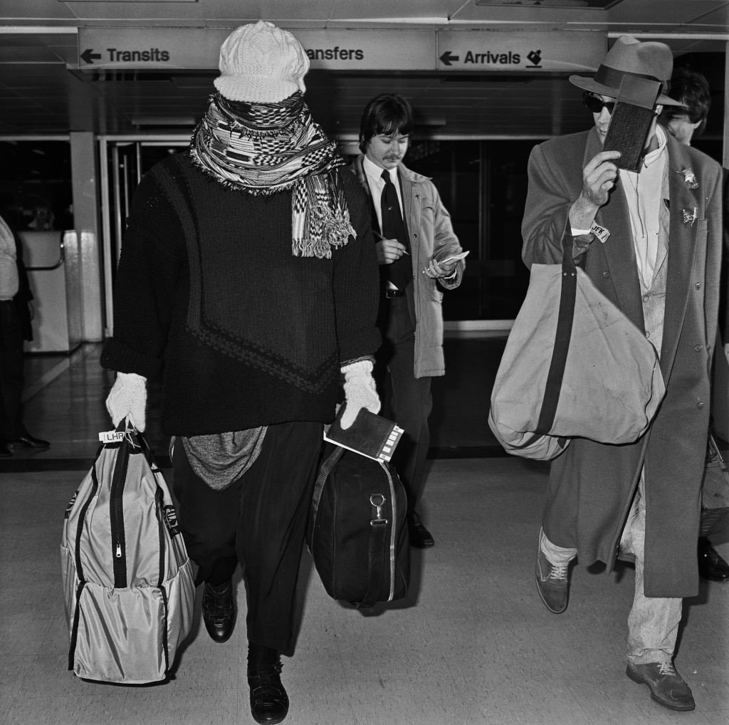 Cantor Boy George chega ao aeroporto de Heathrow em 1985, disfarçando-se com um lenço