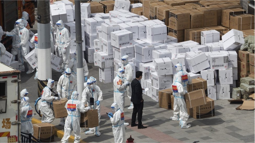 Firemen in PPE carry medical supplies to a temporary warehouse in Shanghai, China Sunday, April 10, 2022