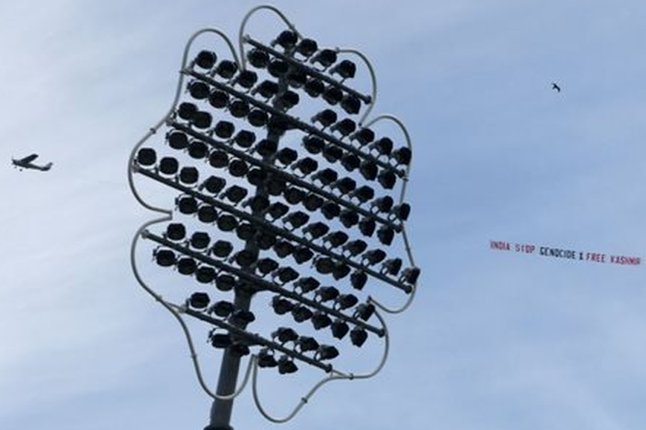 Самолет, летящий над крикетным полем, с надписью «Индия, прекратите геноцид и освободите Кашмир»