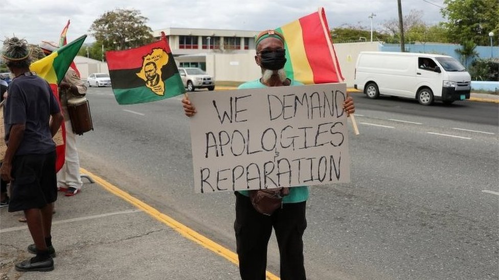 A protester holds a sign during a rally to demand that the United Kingdom make reparations for slavery, ahead of a visit to Jamaica by the Duke and Duchess of Cambridge as part of their tour of the Caribbean, outside the British High Commission, in Kingston, Jamaica March 22, 2022.