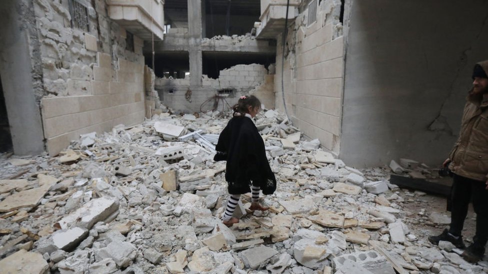 Una niña es vista entre los edificios dañados en el distrito de Afrin de Aleppo.