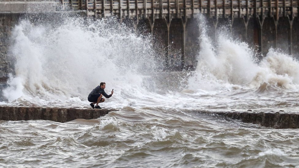 A man takes a photograph of the waves in Dawlish, Devon as gusts of up to 70mph could hit coastal areas as Storm Ellen moves on