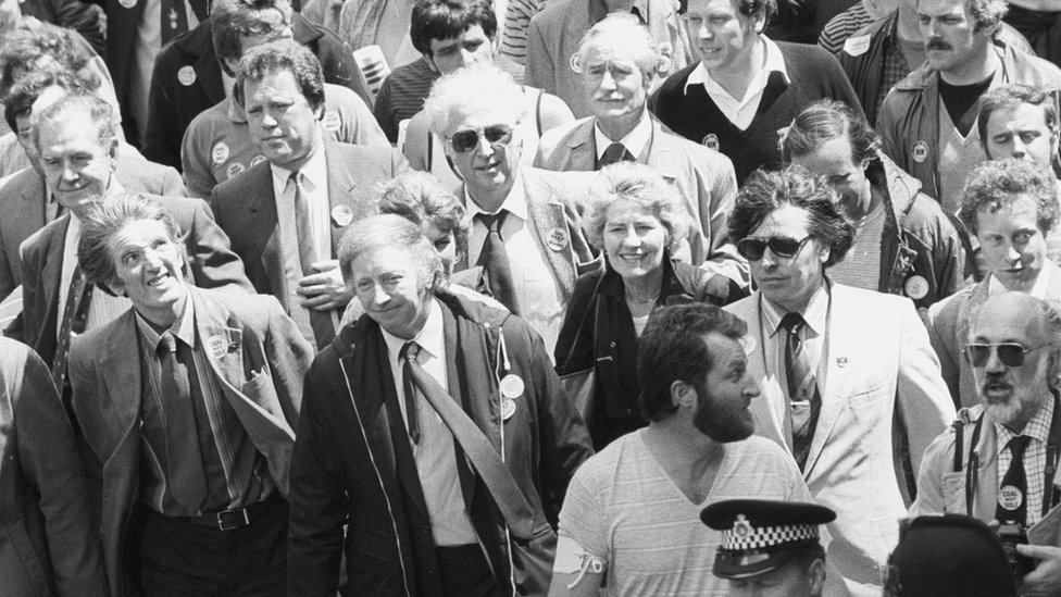 Деннис Скиннер (слева) марширует с президентом горняков Артуром Скаргиллом (второй слева), вместе с 8000 горняков маршем в парламент в 1984 году, чтобы лоббировать депутатов