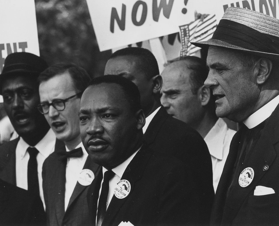 Д-р Мартин Лютер Кинг стоит с другими на марше