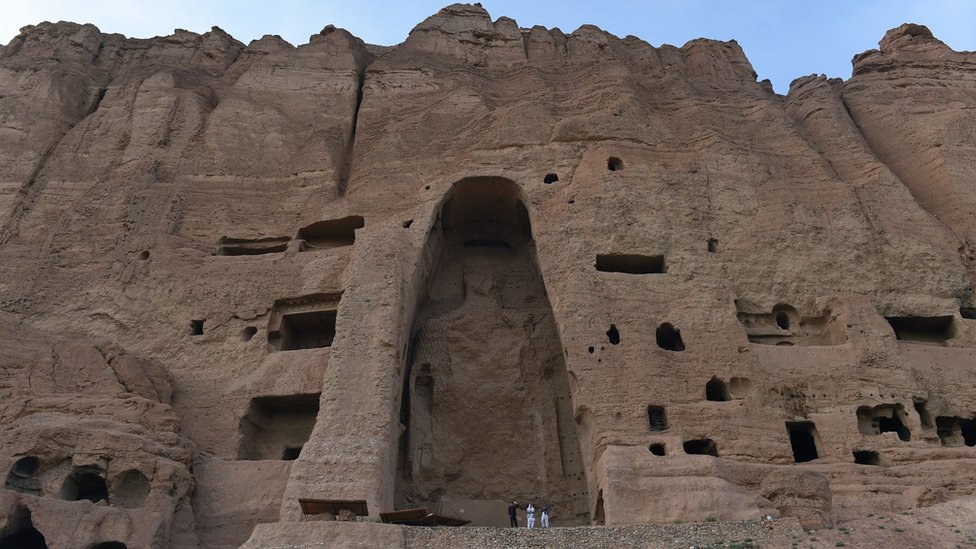 На этой фотографии из архива, сделанной 19 июня 2015 года, видно, как посетители проходят мимо пустого места двух статуй Будды, разрушенных талибами, в Бамиане