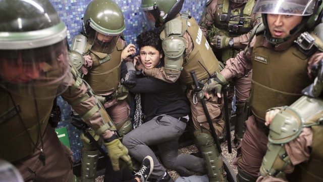 Varios agentes sujetan a un manifestante en el metro de Santiago