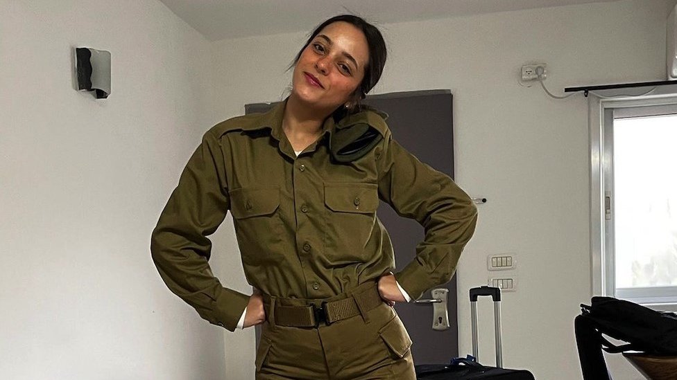 Shai Ashra, posing with hands on hips, in military fatigues