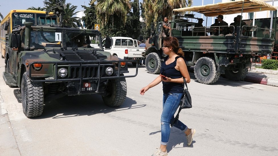 Seorang perempuan berjalan melewati pasukan tentara di luar aula olahraga tempat kotak suara dan alat-alat pemilu dikumpulkan sebelum didistribusikan ke TPS, menjelang pemilihan presiden di Tunis, 14 September 2019.