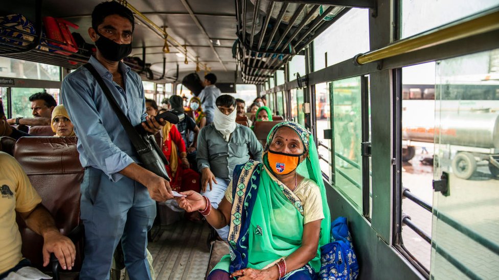 Кондуктор автобуса выдает билеты пассажирке в Уттар-Прадеше.