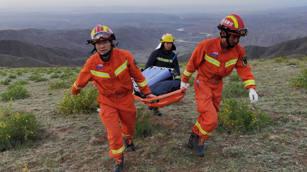 Rescuers carrying equipment as they search for runners who were competing in a 100-kilometre cross-country mountain race when extreme weather hit the area