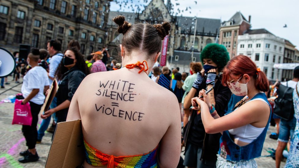 A white protester with the inscription "White silence is violence," on her back.