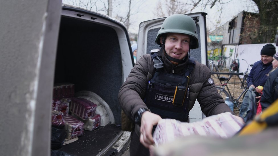 Oleksiy Savkevich entregando una gran bolsa de comida que lleva en una camioneta.