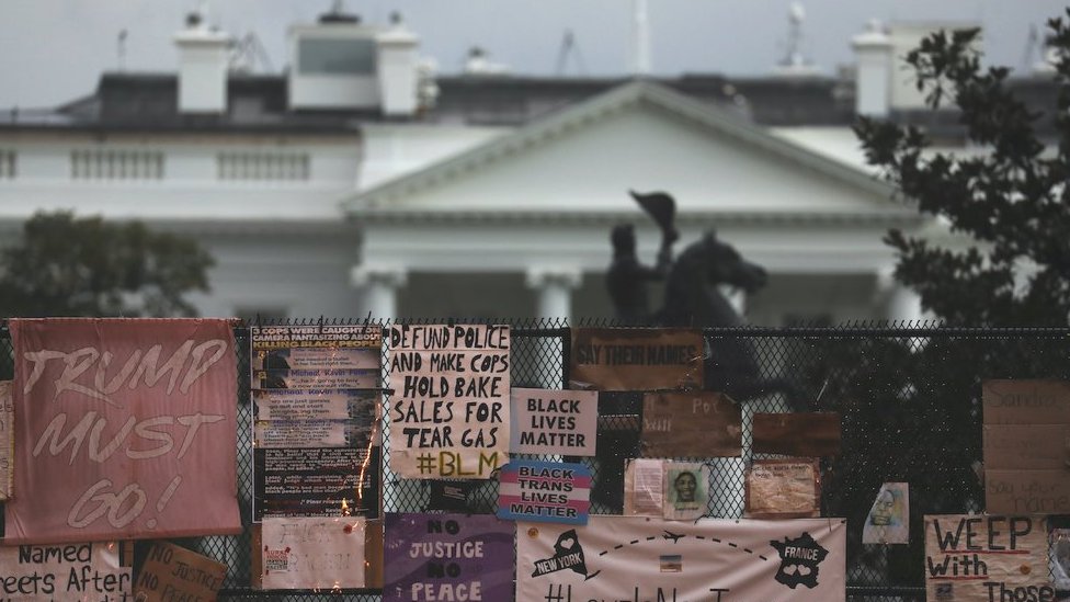 Placards are pictured on a fence in front of the White House, 2 Oct 2020