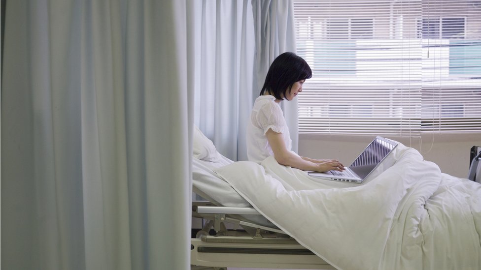 Una mujer joven con una computadora en una habitación de un hospital.