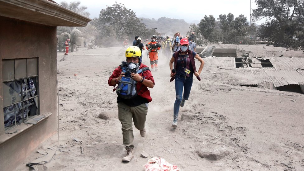 Media members reacts at an area affected by the eruption of the Fuego volcano in the community of San Miguel Los Lotes in Escuintla, Guatemala June 5, 2018.