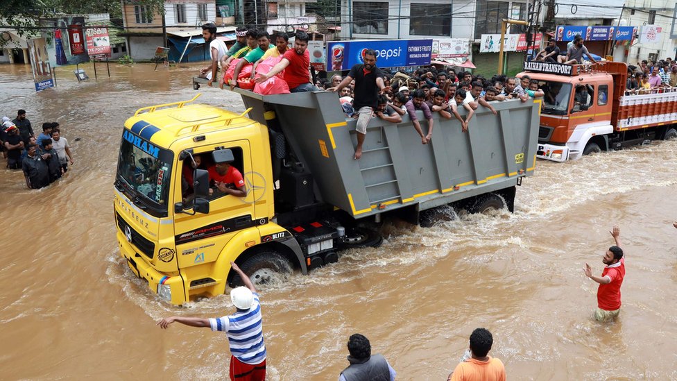 Indian passengers travel in a truck to a safer place as flood waters ravage the National Highway 47 in Ernakulam district of Kochi