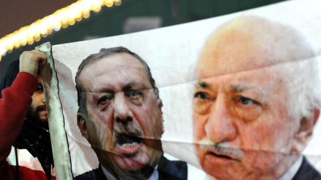 Un manifestante contra el gobierno muestra una pancarta con las imágenes de Erdogan y Gülen.
