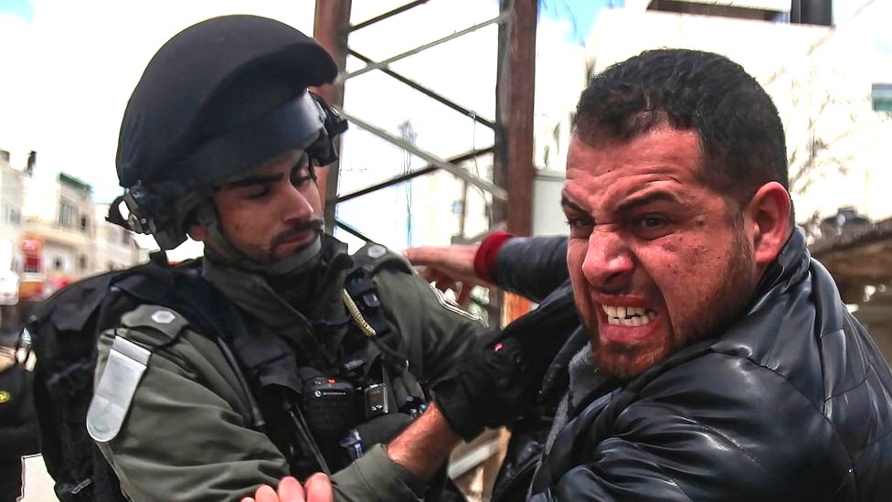 An Israeli soldier quarrels with a Palestinian demonstrator