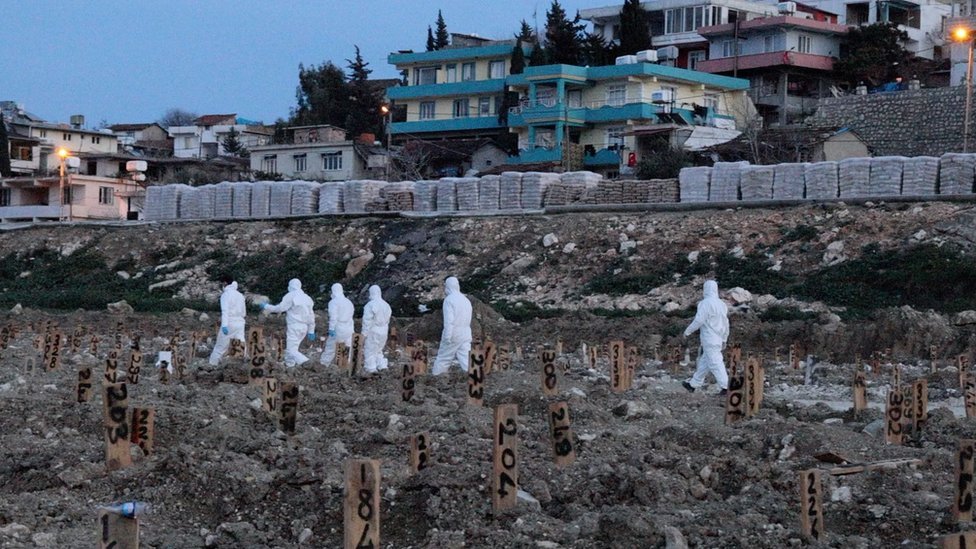 TRabajadores en trajes blancos en el cementerio de Narlica