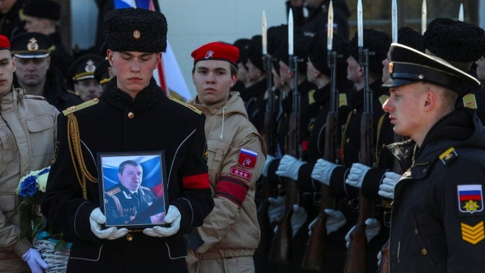 A man carries a picture of the fallen serviceman
