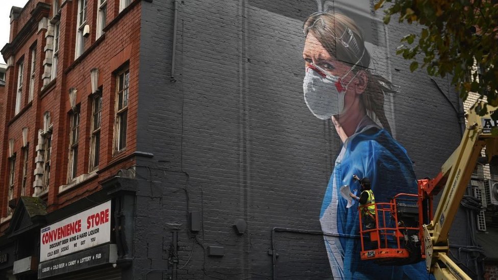 An artist creates a mural of a National Health Service worker on a wall in north Manchester on 17 October 2020, as the number of cases of the novel coronavirus COVID-19 rose.