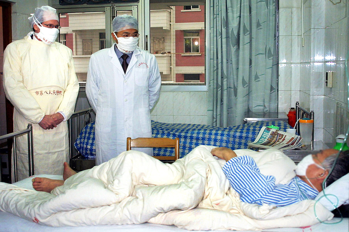 Robert Maguire, da OMS, e médico chinês visitam paciente com Sars em Guangzhou em abril de 2003