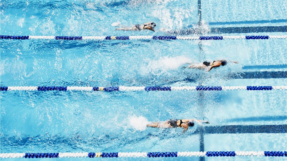 Pessoas nadando em piscina com raias
