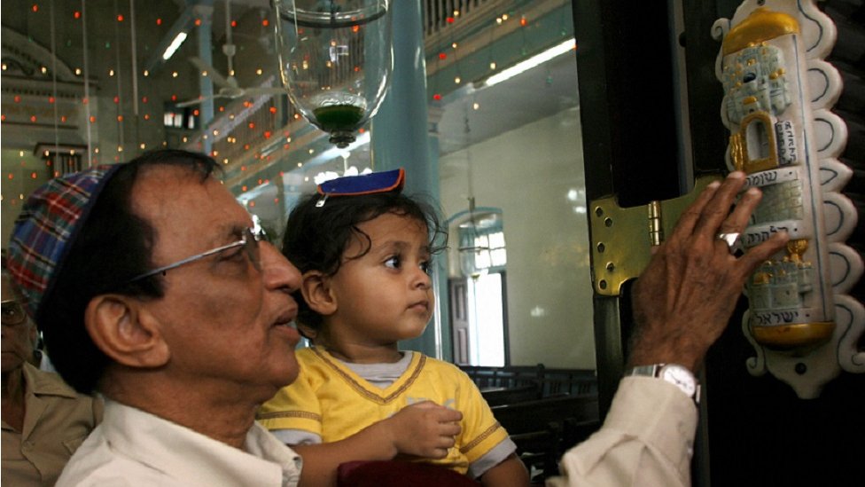 Seorang Yahudi India bersama anaknya sedang menyentuh mezuzah di sebuah sinagog.