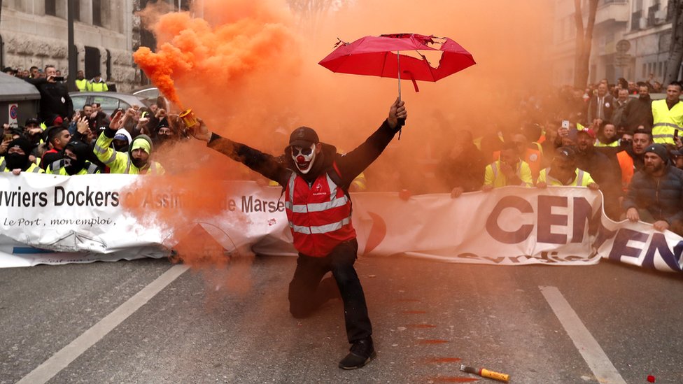 Протестующий держит дымовой факел во время демонстрации против пенсионных реформ в Марселе, Франция, 5 декабря 2019 г.