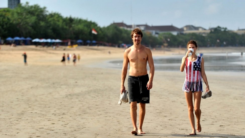 Иностранные туристы гуляют по пляжу