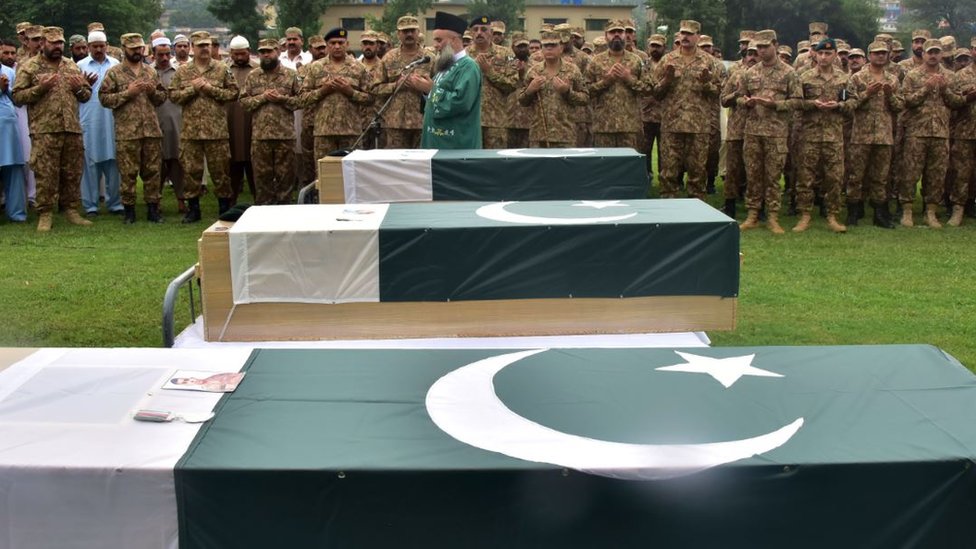 Un oficial de ejército paquistaní reza con soldados frente a los féretros de tres colegas muertos en un intercambio de fuego en la frontera