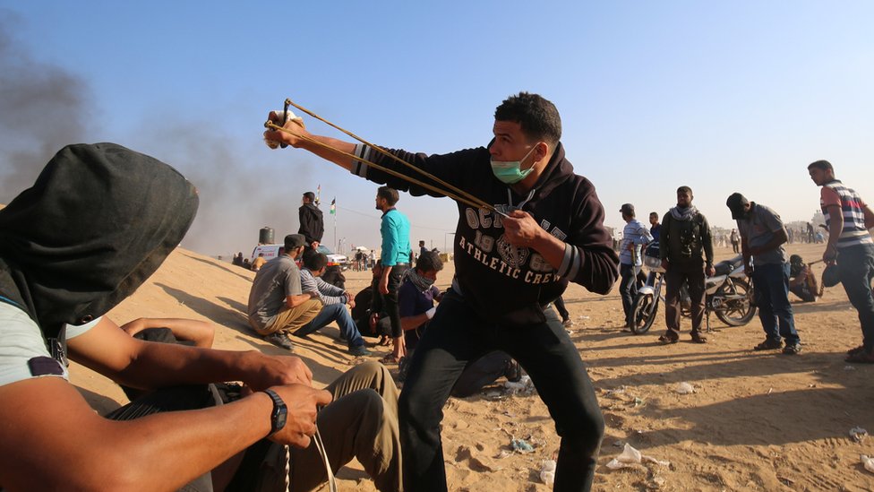 Un palestino lanza una piedra en la frontera entre Israel y Gaza