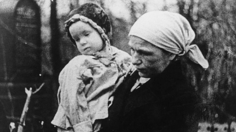 A woman carries a child during the Siege of Leningrad