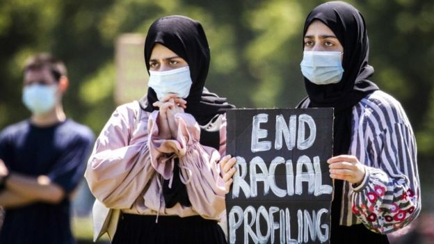 فتاتان تحملان لافتة كتب عليها أنهوا العنصرية
