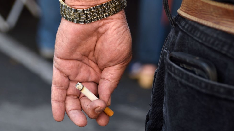 Un hombre sostiene un cigarrillo en su mano.